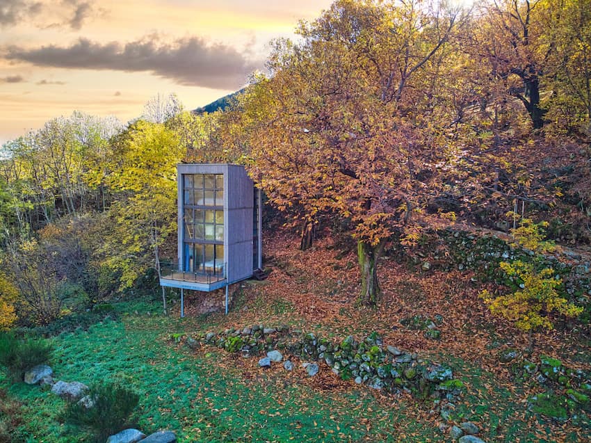 Cabane insolite contemporaine en Ardèche avec grande verrière, vue aérienne d'un hébergement atypique niché en lisière de forêt aux couleurs de l'automne.